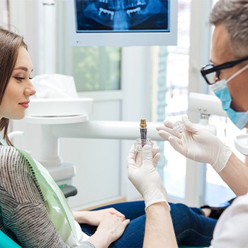 A dentist showing a dental implant to his female patient