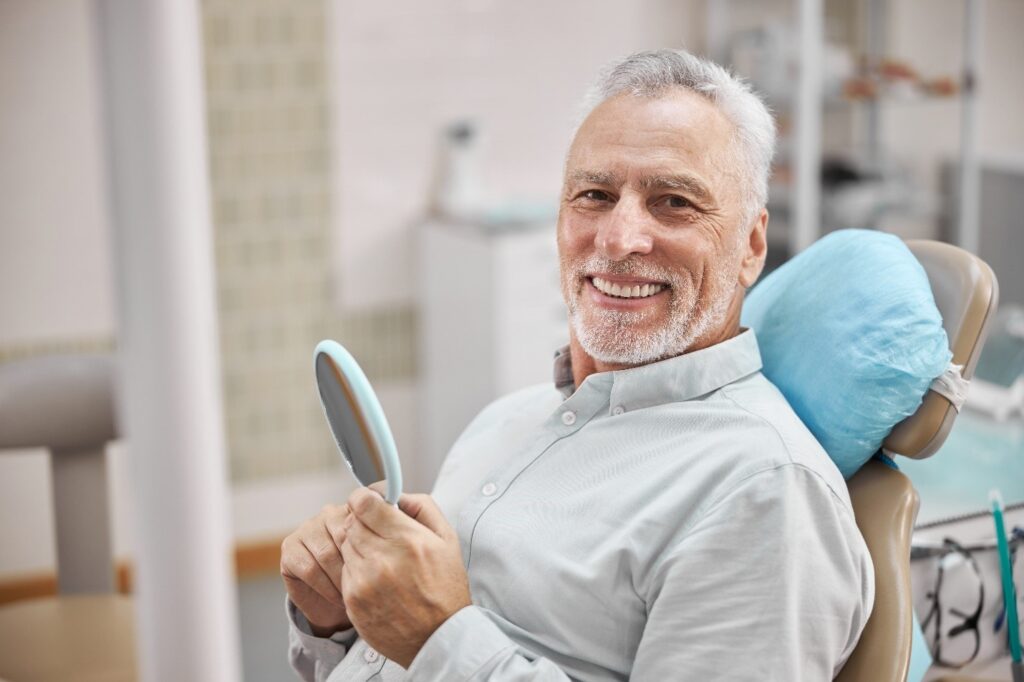 patient smiling while looking in dental mirror 